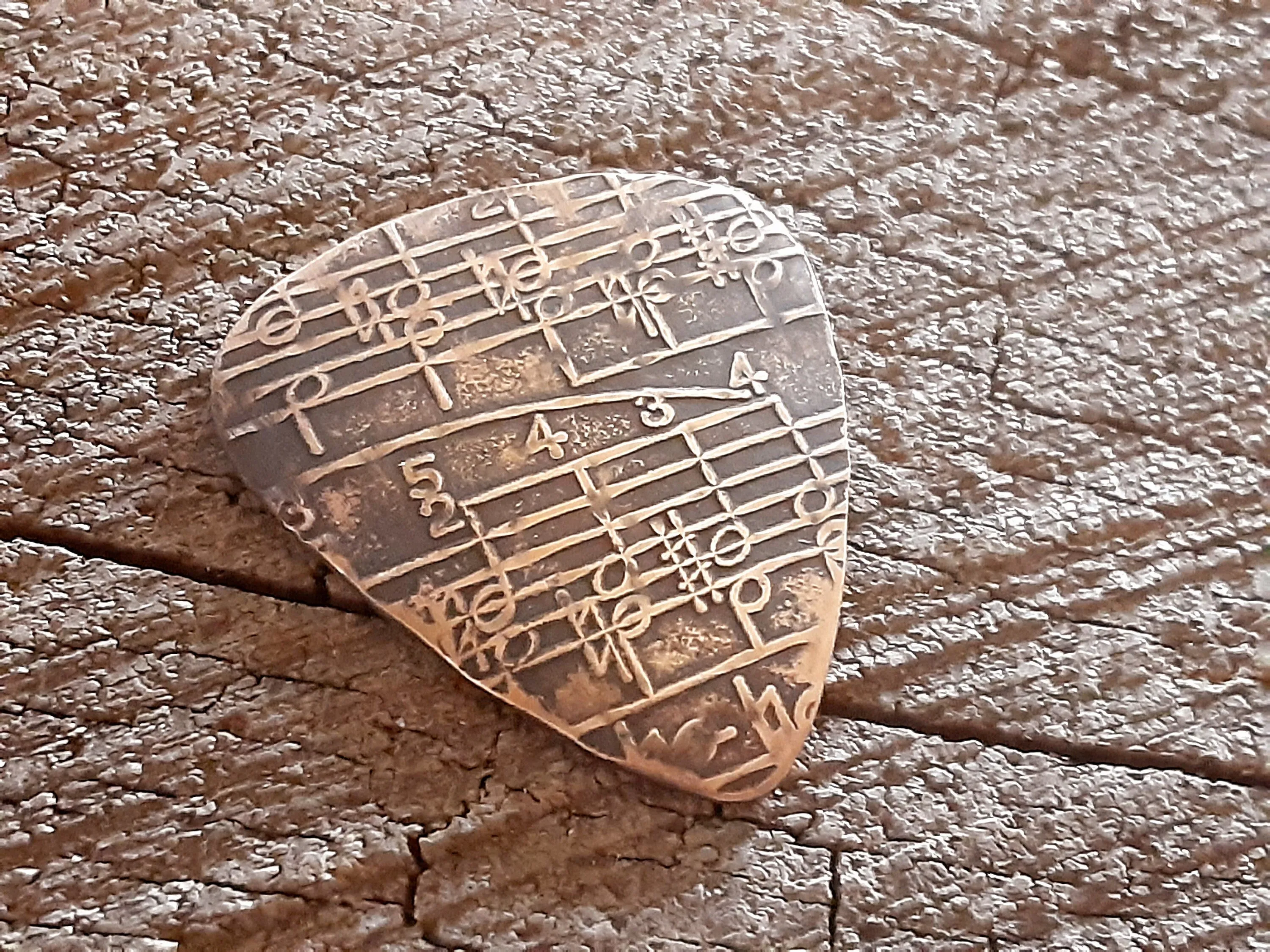 Guitar pick in Bronze with music notes